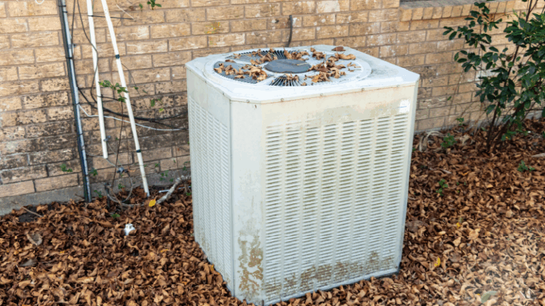 a dirty outdoor air conditioning unit covered in leaves