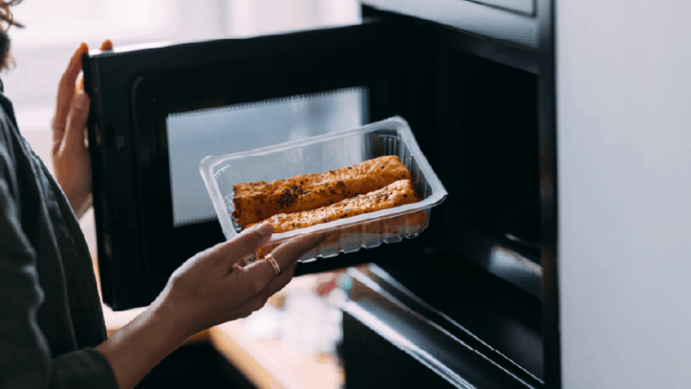 woman putting a dish into the microwave